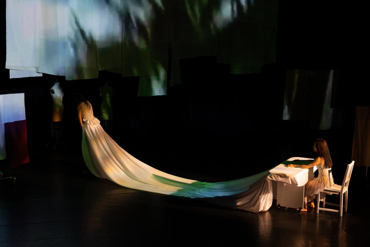 Two dancers conected by cloth, draping down dancers back