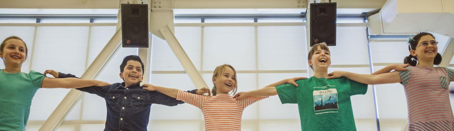 Five young dance students link arms